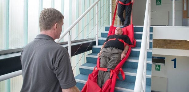 Elderly patient being evacuated down stairs in rescue-sheet